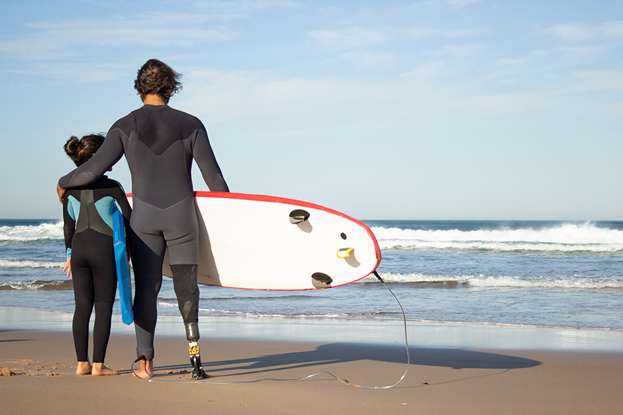 Loving father with mechanical leg with daughter on beach